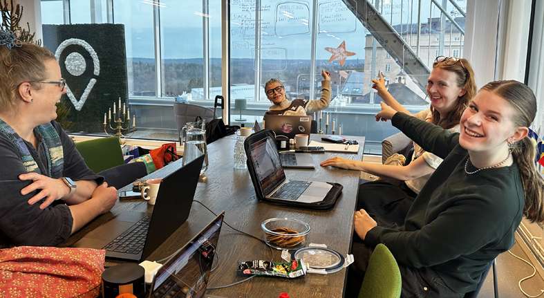 Four people sitting around a conference table with laptops, one person holding up a star-shaped object