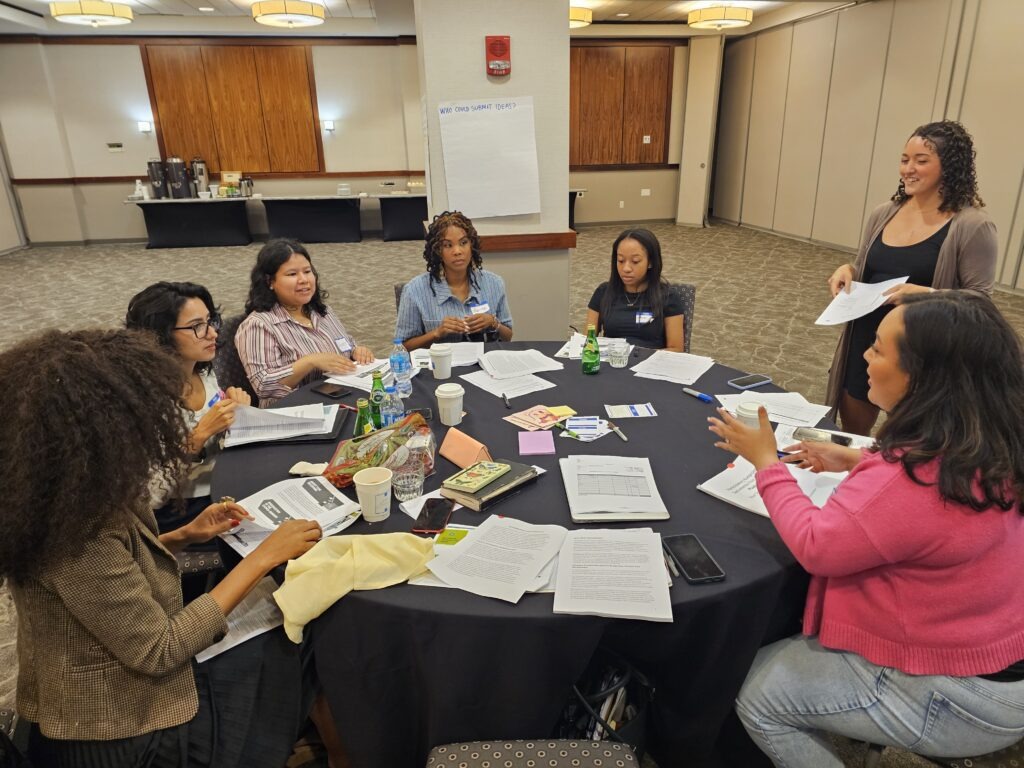 Diverse group of PB Seeds participants gathered around table in working session with papers and materials